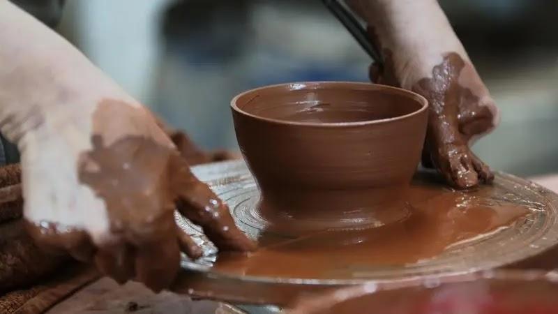 Hands shaping clay bowl on pottery wheel
