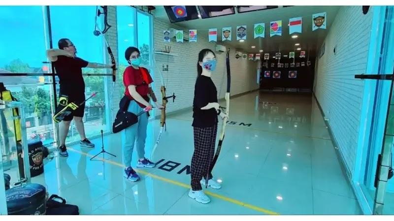 Three masked archers in indoor archery range