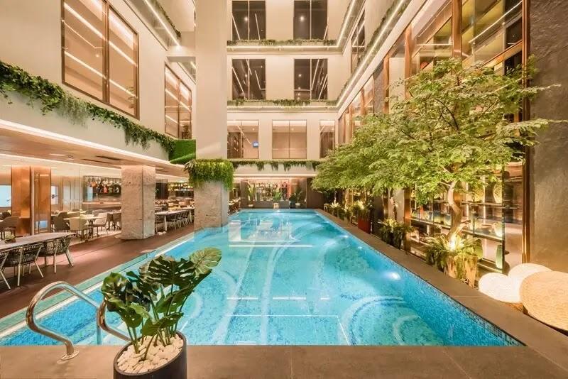Indoor hotel pool atrium with greenery and seating