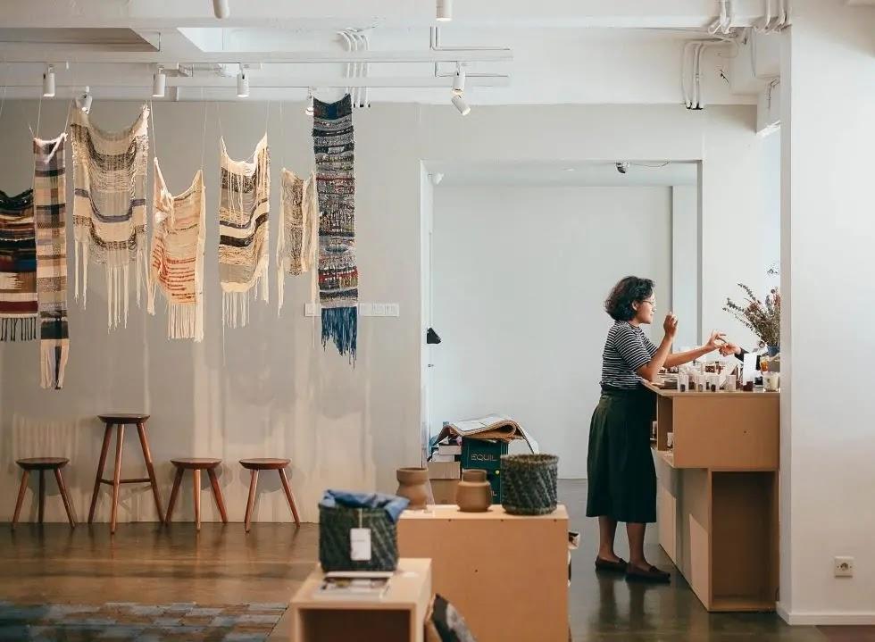 woman arranging products in a gallery with woven hangings