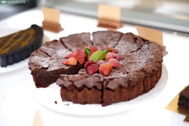 Chocolate tart with sliced strawberries on white plate