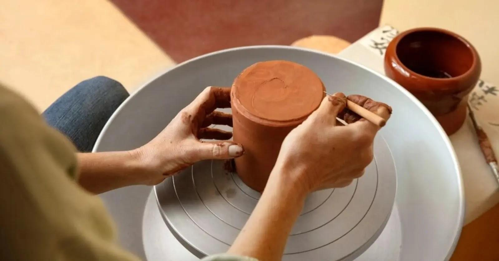 Hands shaping clay on a pottery wheel