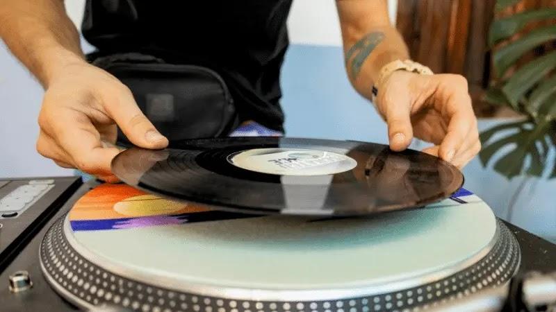 Hands placing vinyl record on DJ turntable