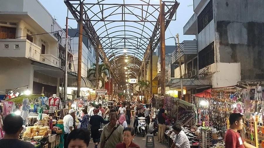crowded street market under arched canopy at dusk