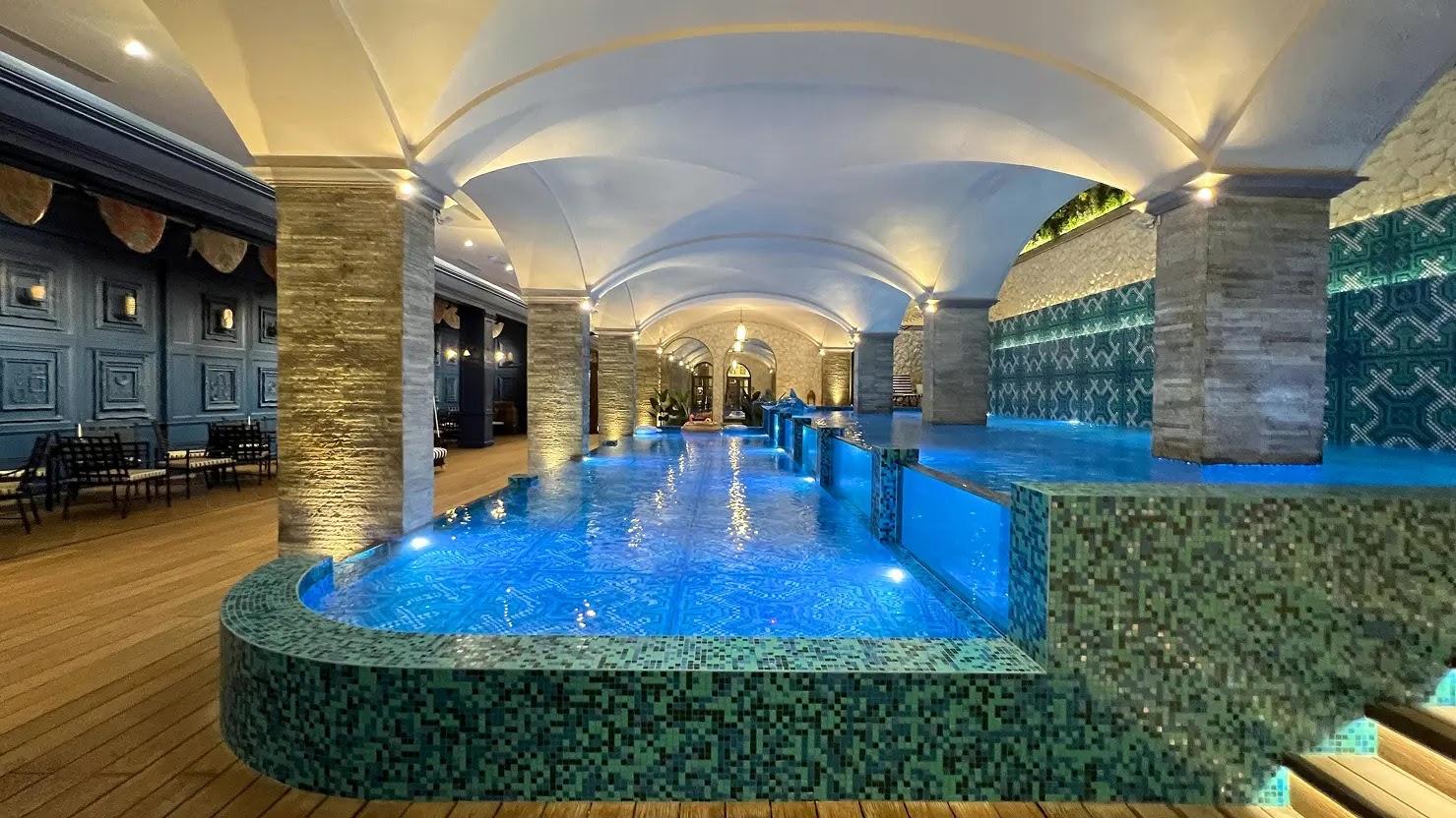 luxury indoor pool with blue mosaic tiles and arches