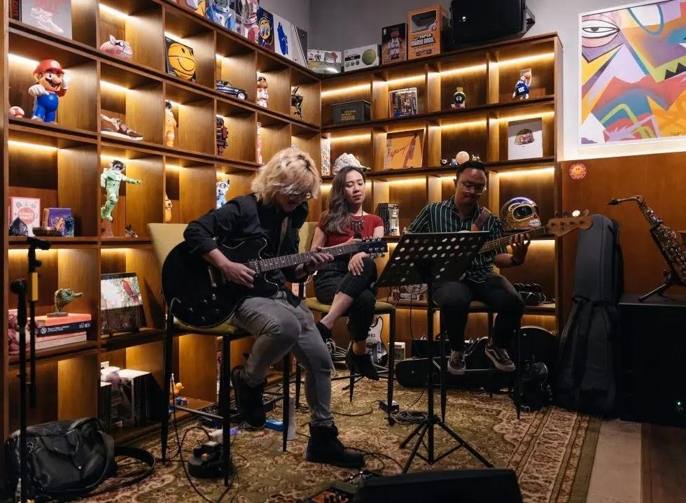 trio of musicians playing guitars in cozy room