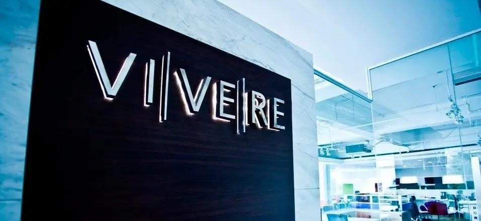 VIVERE office logo on dark wall in modern workspace
