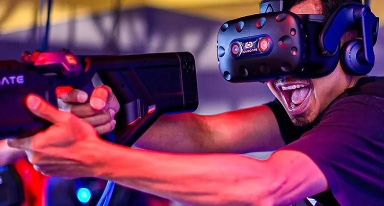 Excited man wearing VR headset aiming gaming rifle