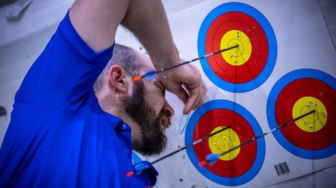 Person in blue shirt inspecting arrows on archery targets