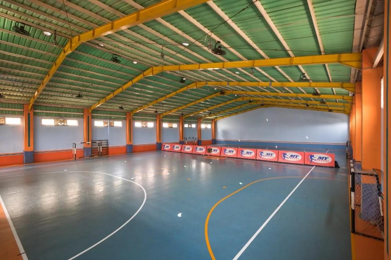 Indoor futsal court with blue floor and yellow beams