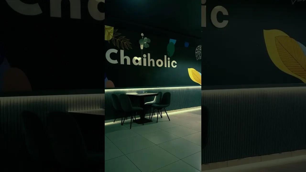 Chaiholic logo on cafe wall above table and chairs
