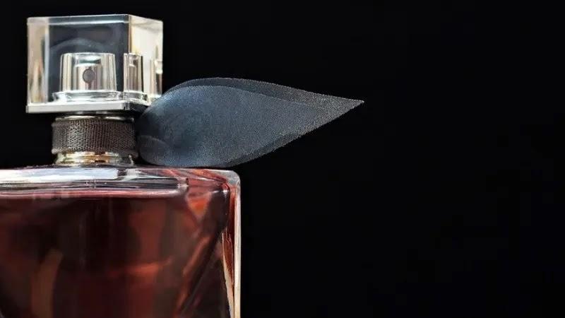 glass perfume bottle with black ribbon on dark background