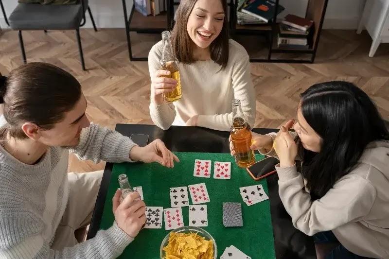 Three friends drinking beer and playing cards
