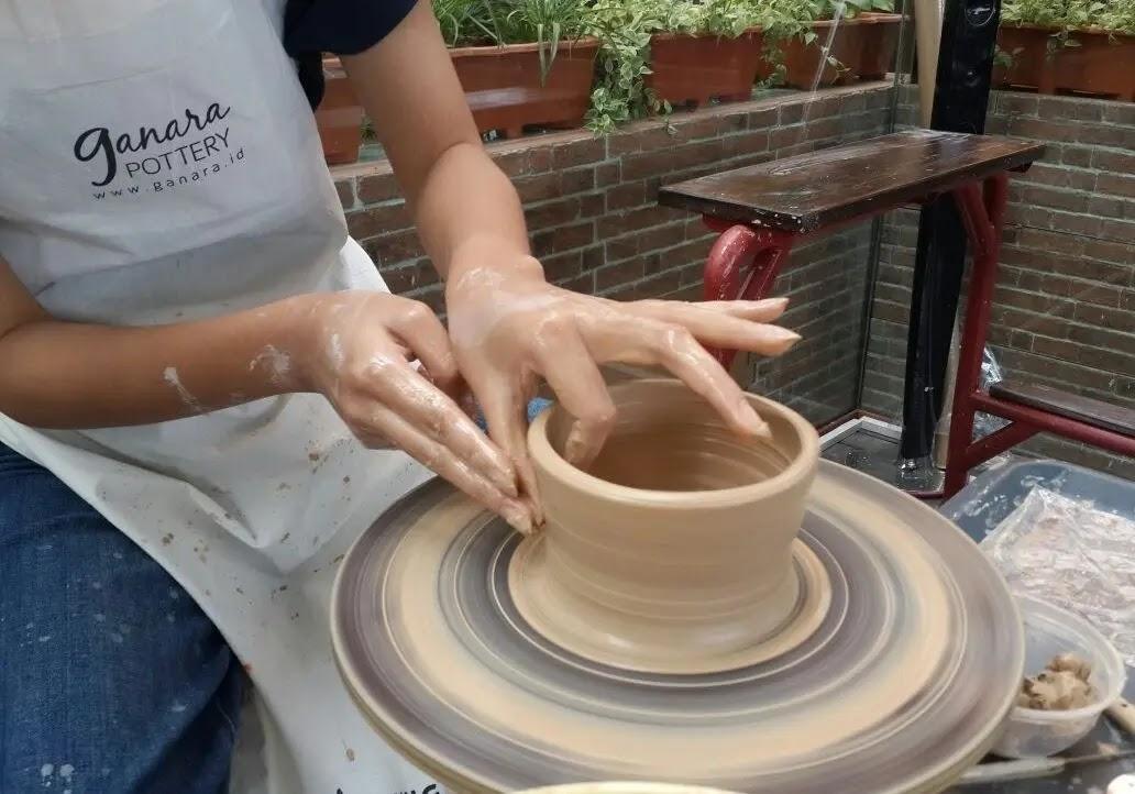 Hands shaping pottery on a spinning potter's wheel