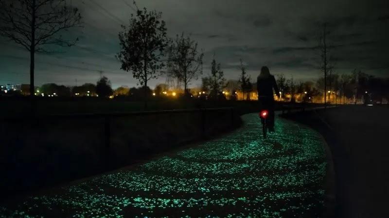Cyclist on glowing green starry bike path at night