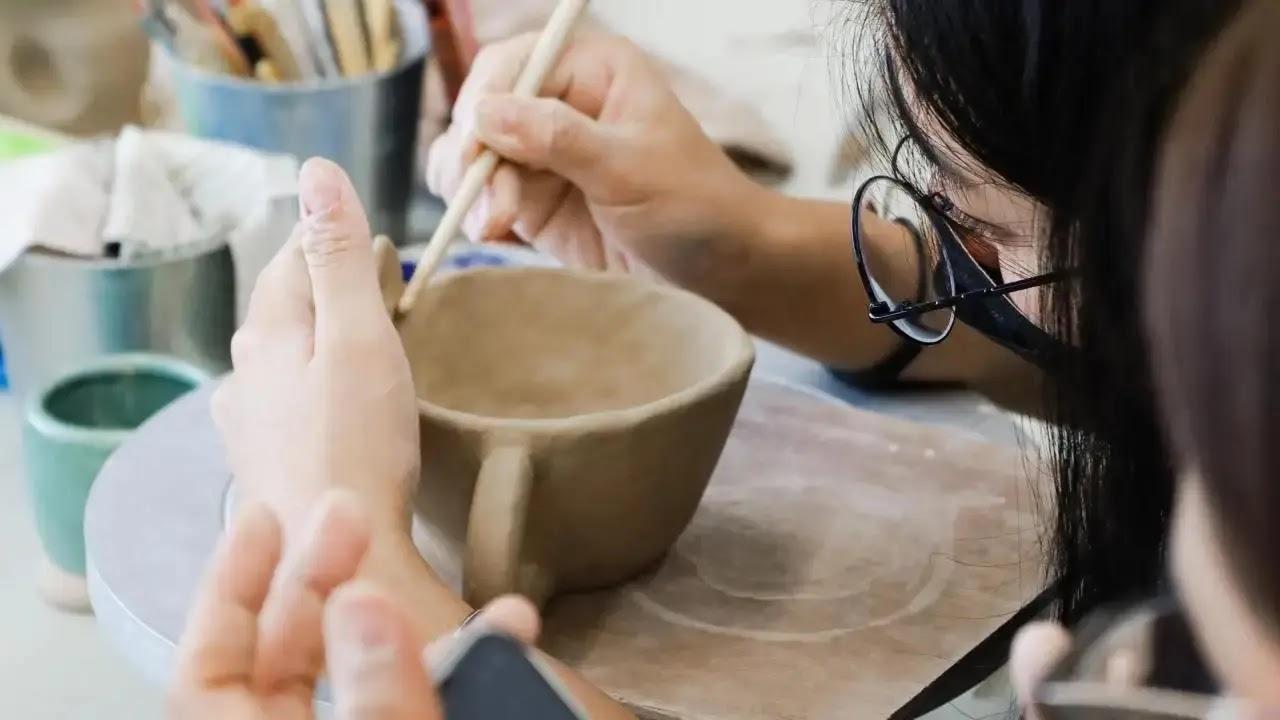 Person shaping a clay mug in pottery class