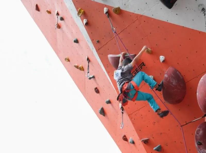 young climber on orange indoor climbing wall