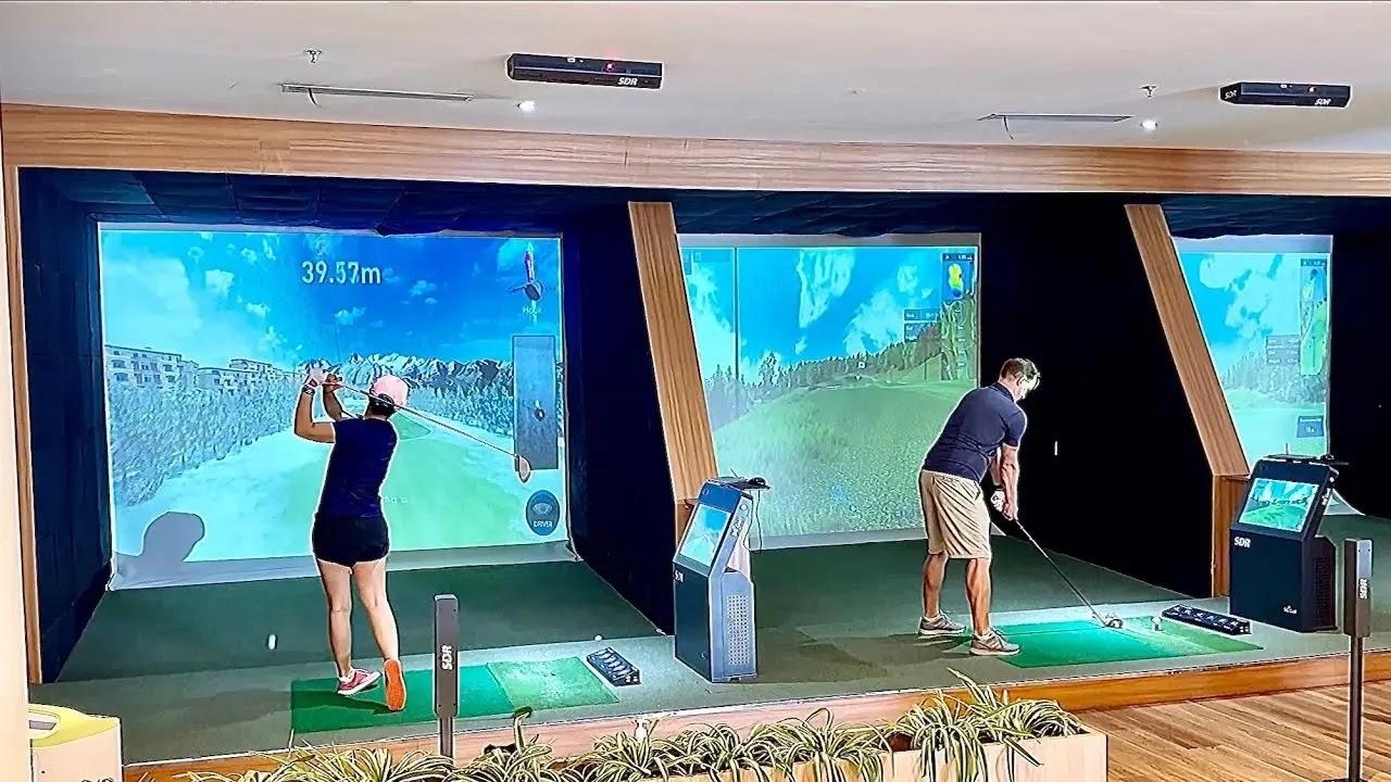 Two people playing on indoor golf simulators