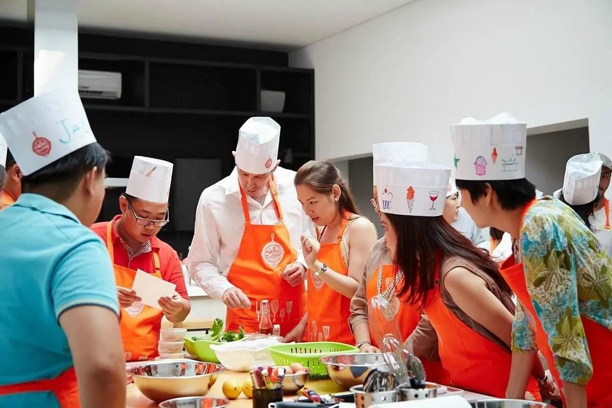 people in chef hats and orange aprons cooking together