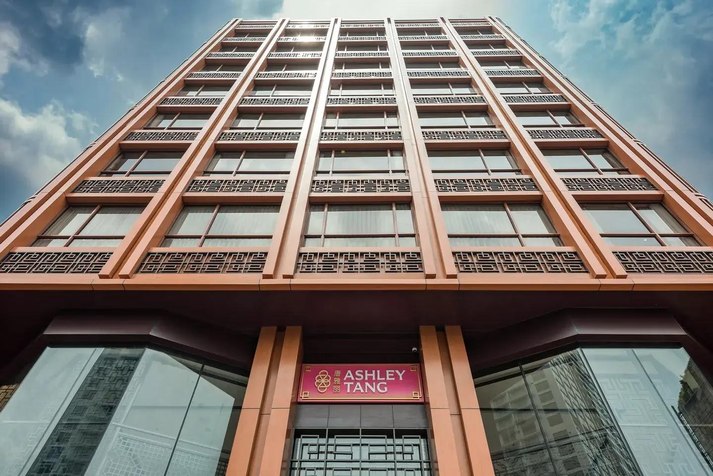 Facade of tall building with pink logo sign above entrance