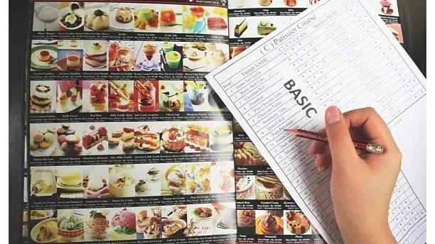 Hand filling BASIC pastry worksheet over dessert menu