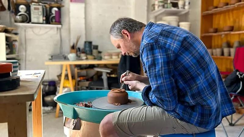 potter shaping clay on a pottery wheel in studio