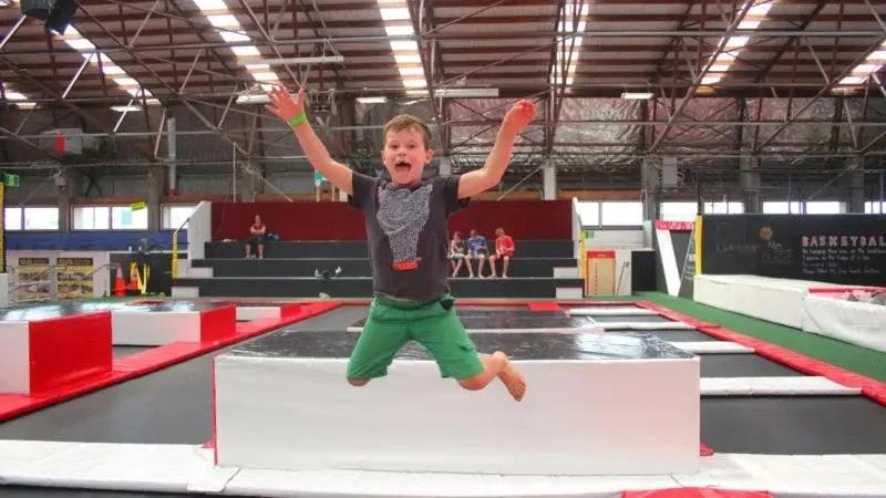 young boy mid-jump at indoor trampoline park