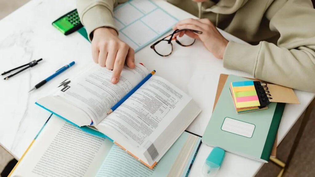 Student studying with open textbooks and stationery