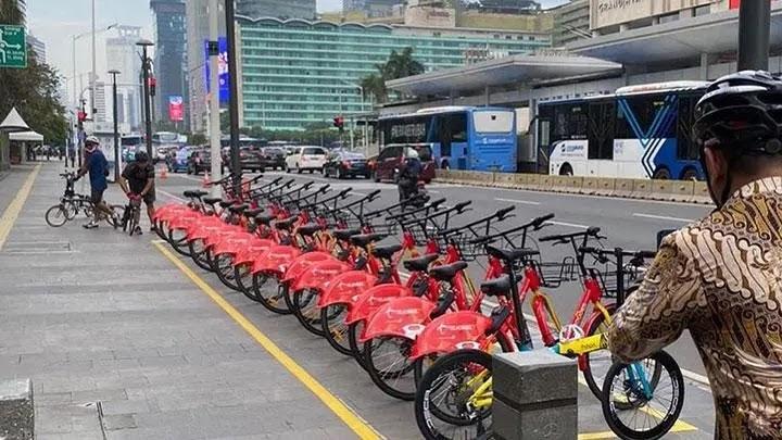 Row of red rental bikes parked along city sidewalk