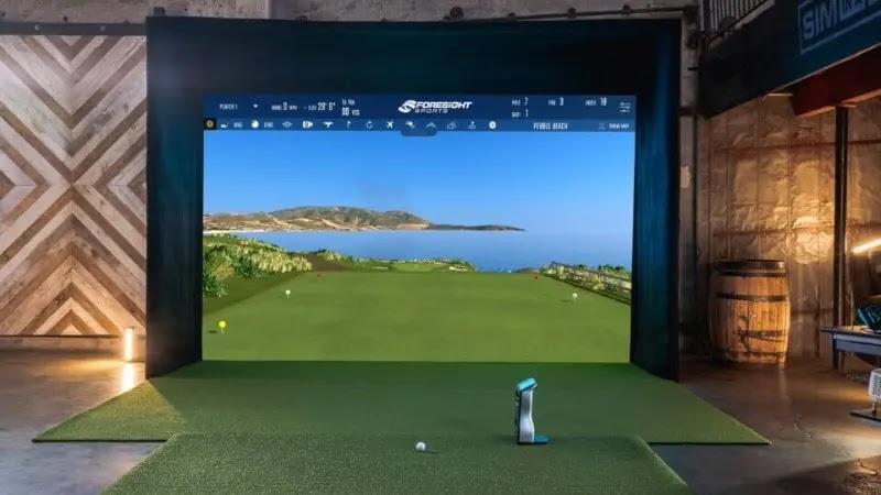 Indoor golf simulator with screen showing coastal course