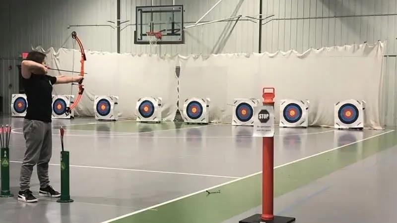 person shooting bow at indoor archery targets