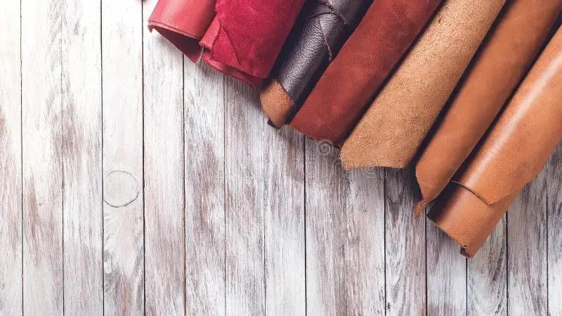 Rolled leather hides on white wooden background