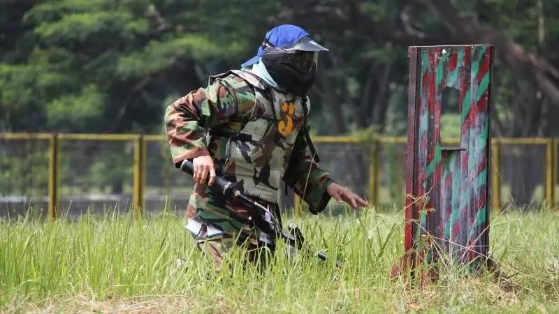 Paintball player in camouflage mask crouching in grass