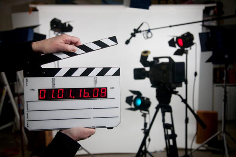 Video production set with clapperboard and studio cameras, plus countdown timer display on monitor