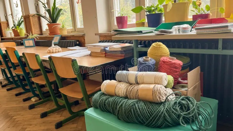 Wool yarn balls in assorted colors stacked on a craft table in a bright classroom workspace