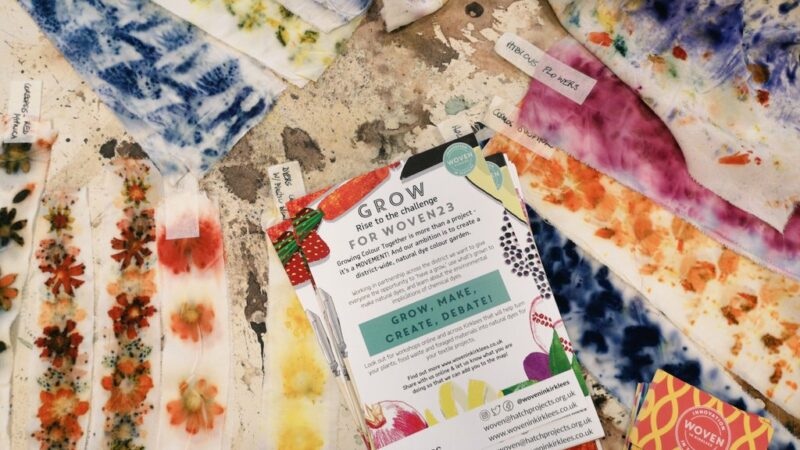 Colorful handmade fabric swatches spread on a table around a printed brochure titled “GROW for Women 2023”