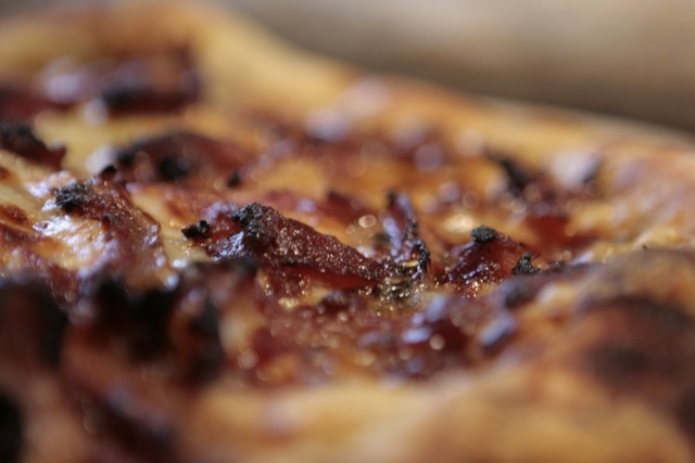 Close-up of sizzling roasted meat slices with browned crispy edges and juices bubbling