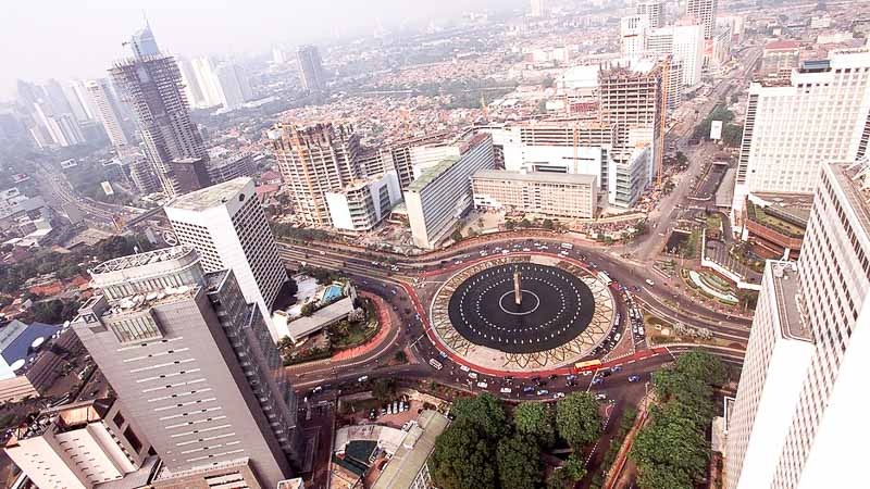 Aerial view of Bangkok’s central plaza with a circular fountain, city streets, and tall buildings surrounding it