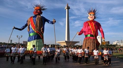 Traditional street dancers in colorful costumes with a monument tower in the background at dusk
