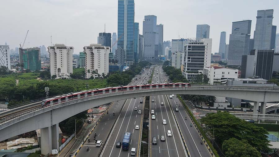 Elevated highway with traffic and red commuter train passing bridges amid downtown skyline buildings