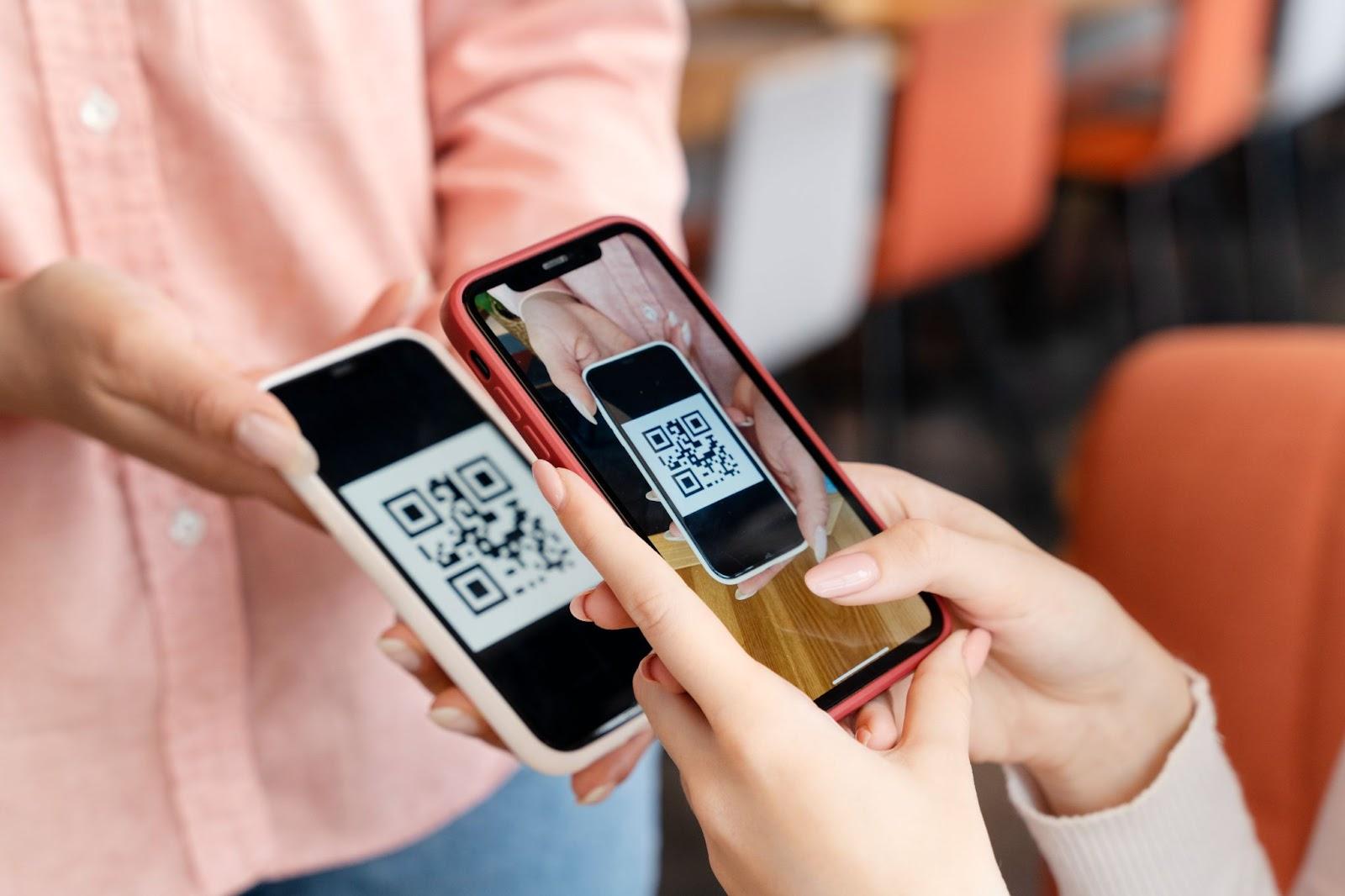 People scanning QR codes on smartphones in a cafe, using mobile payments and digital check-ins