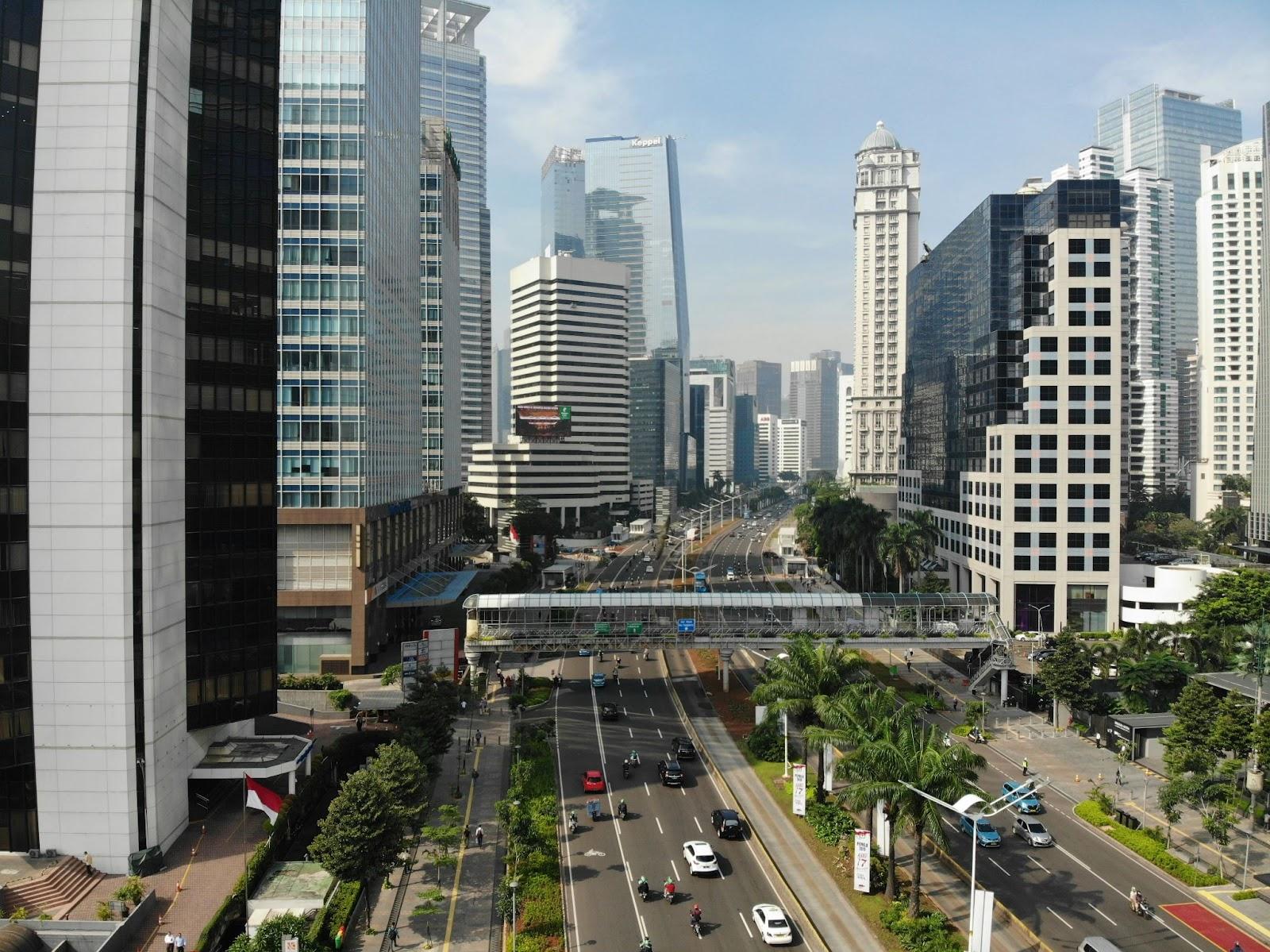 Downtown city skyline with busy multi-lane road, office towers, and elevated transit track under daylight sky