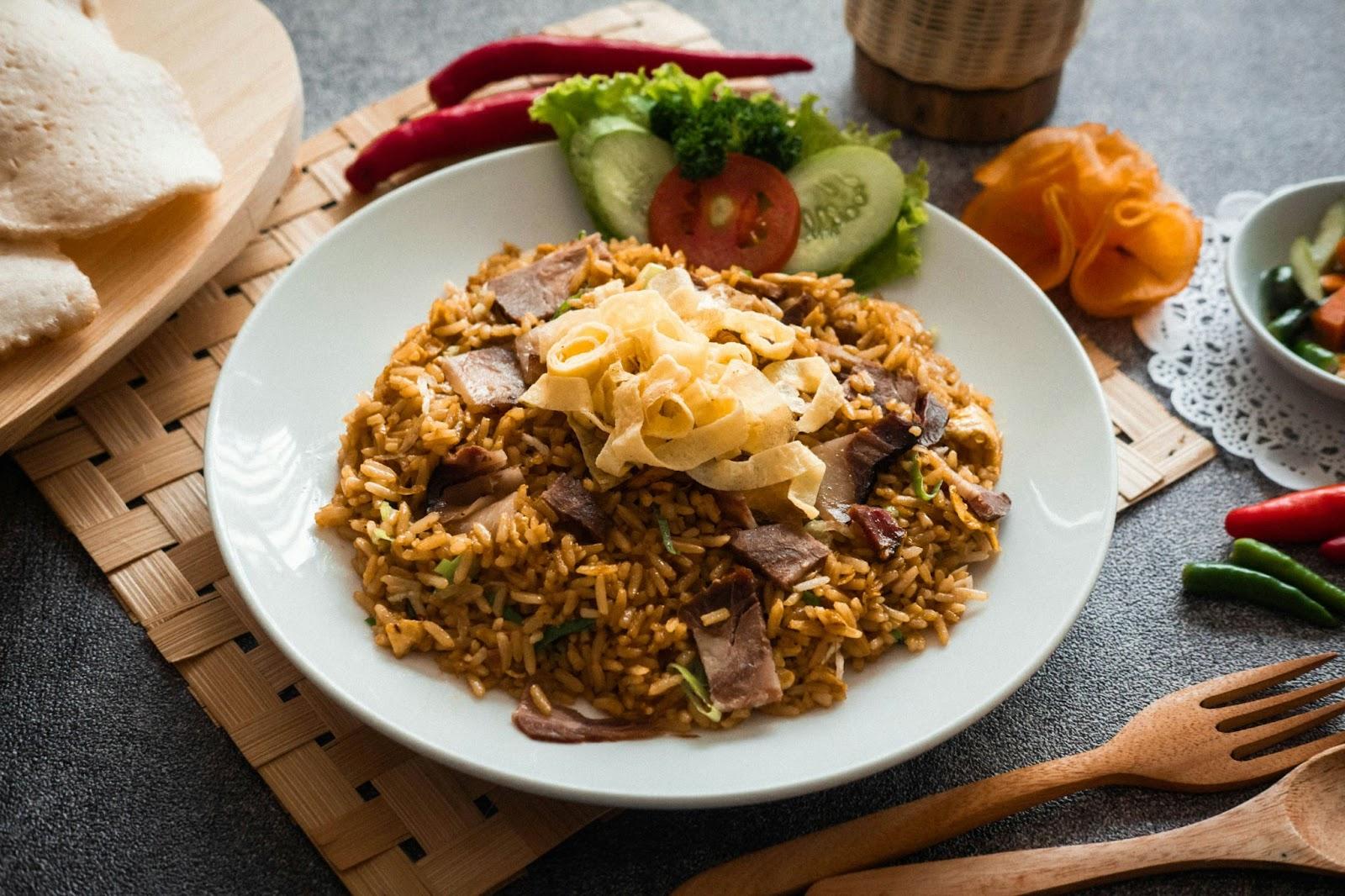 Hakkar rice dish with beef, fried onions, crispy egg strips, and fresh salad on a white plate