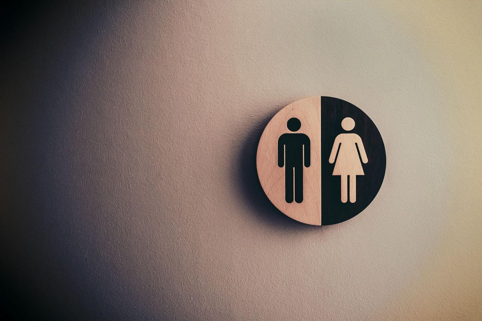 Single gender restroom sign with male on left and female on right, mounted on textured wall