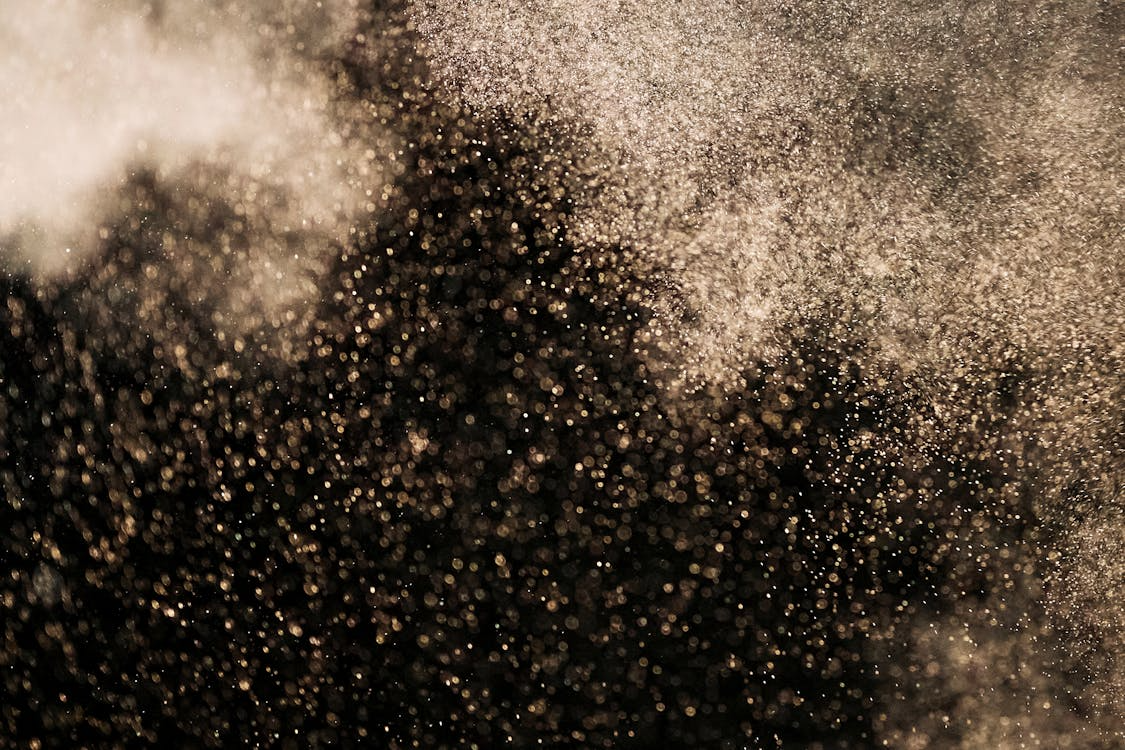 Golden dust particles swirling in a smoky air stream background, cinematic light haze texture