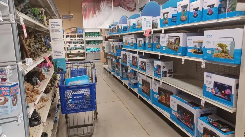 Pet supply aisle with blue promotional displays, shelves of aquarium and terrarium products, and shopping cart inside store