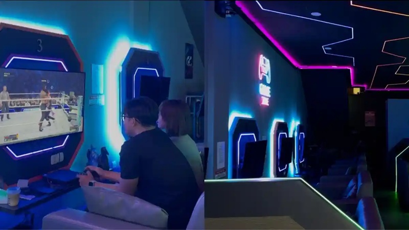 immersive VR gaming area with neon-lit controls, two players seated, and a large screen display