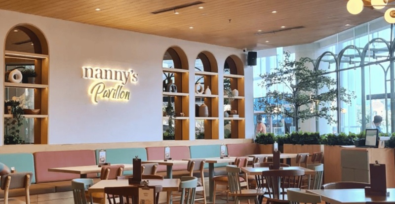 Nanny’s Pavillon restaurant interior with arched shelves, warm wall sign, and neatly set wooden tables and chairs