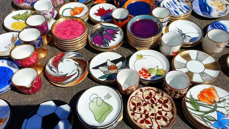 Colorful mixed ceramic plates and teacups arranged on a table, featuring blue, floral, and decorative designs