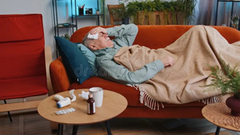 Man relaxing on an orange sofa with blanket and mug at a modern living room coffee table